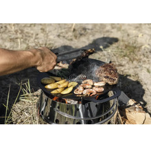 Person grillt Steaks, Kartoffeln und Garnelen auf einer Feuerplatte