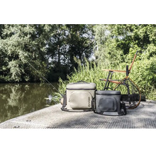 Szene mit zwei Petromax Kühltaschen, einem Angelstuhl, einem Kescher und einer Angel am Wasser