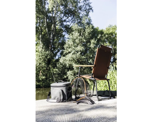 Szene mit Angelstuhl, Kühltasche und Kescher am Wasser
