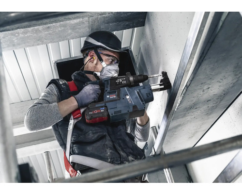 Ein Handwerker bohrt mit einem Bohrhammer ein Loch in eine Wand.