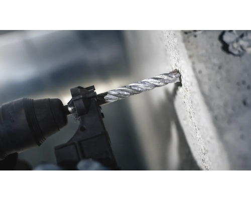 Nahaufnahme einer Bohrmaschine mit Betonbohrer beim Bohren in eine Betonwand
