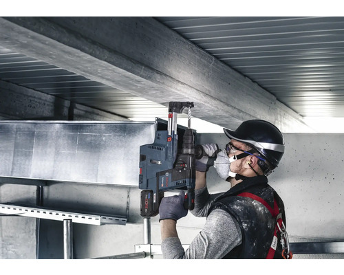 Bohrarbeiten an einer Betondecke mit einem Bohrhammer und Bohrständer durch einen Handwerker.