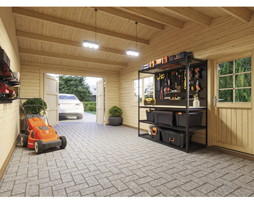 Vue intérieure d''un garage avec des outils, une tondeuse à gazon et une voiture devant la porte ouverte