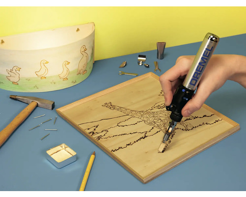 Fer à souder Dremel gravant une pièce de bois, outils et décoration sur une table