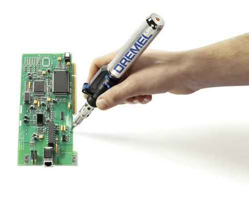 Une main soude une carte de circuit imprimé avec un fer à souder Dremel.