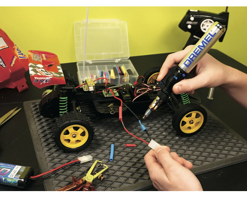 Réparation d''une voiture télécommandée avec un fer à souder et des outils.