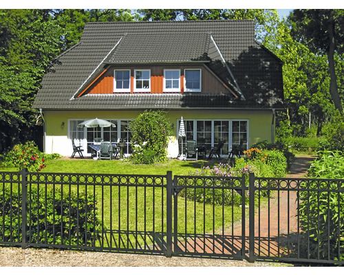 Maison individuelle avec jardin, clôture métallique et mobilier de jardin