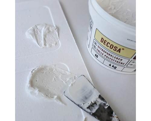 Colle polystyrène Decosa avec spatule et restes de colle sur une palette