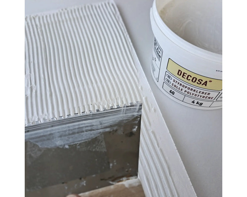 Colle polystyrène Decosa en seau à côté d''une surface enduite