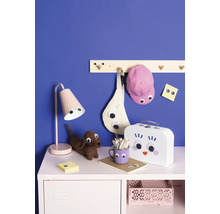 Kinderzimmer mit Tischleuchte, gehäkeltem Dackel, Federmäppchen, Notizblock, Lunchbox und Garderobe mit Accessoires.