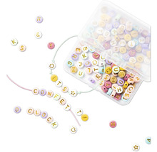 Diverses perles alphabet colorées dans une boîte en plastique transparente et sur des cordons.