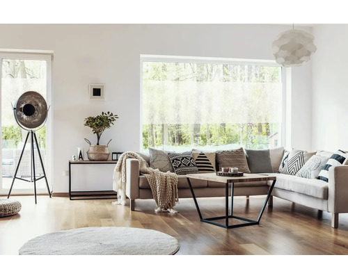 Salon avec canapé, coussins, table basse, lampadaire et fenêtre