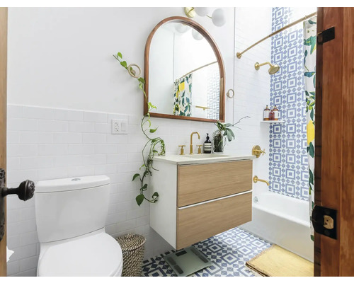 Badezimmer mit Toilette, Waschtischunterschrank, Spiegel und Badewanne unter einer Dusche mit Duschvorhang