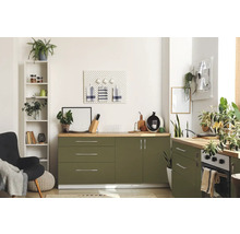 Cuisine lumineuse avec armoires vertes, plans de travail en bois et divers objets de décoration