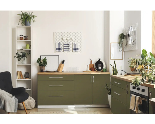 Cuisine lumineuse avec armoires vertes, plans de travail en bois et divers objets de décoration