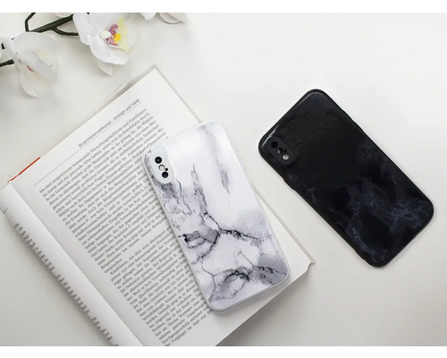 Deux coques de téléphone portable avec motif marbré reposent sur un livre ouvert.