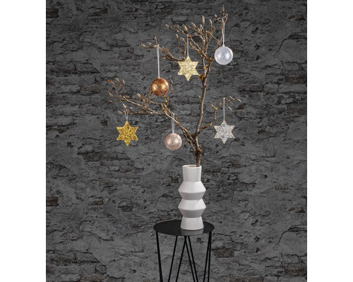 Scène de décoration avec des branches dans un vase et des étoiles ainsi que des boules comme décorations de Noël