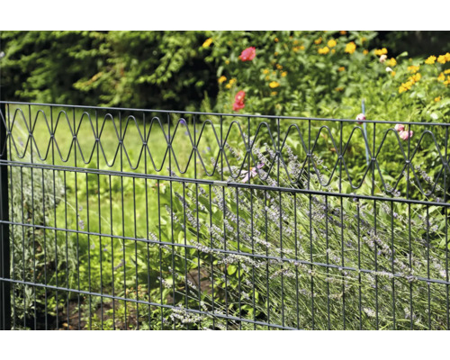 Gartenzaun mit dekorativem Oberteil vor Grünpflanzen