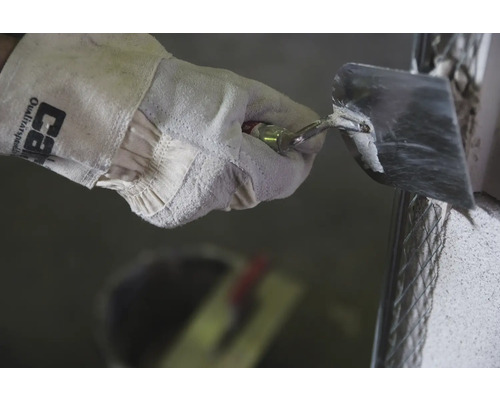 Main avec gant de travail et truelle lors du plâtrage