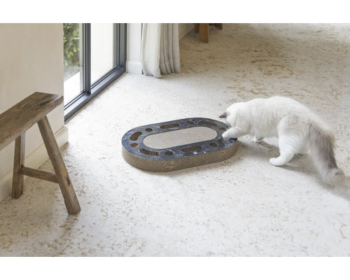 Chat jouant avec un griffoir ovale en carton avec des trous