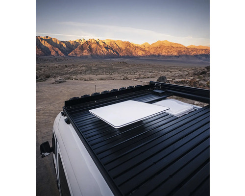 Galerie de toit sur un véhicule avec table et récipient devant un paysage de montagne