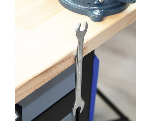 Une clé à fourche est suspendue à un établi.