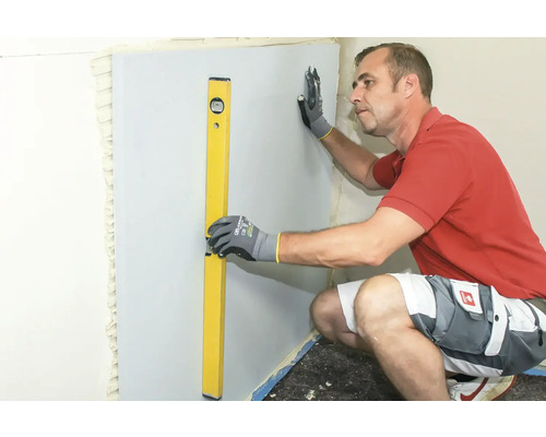 Handwerker richt Trockenbauwand mit Wasserwaage aus