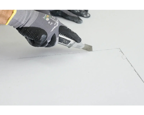 Hand mit Schutzhandschuh schneidet Material mit einem Universalmesser