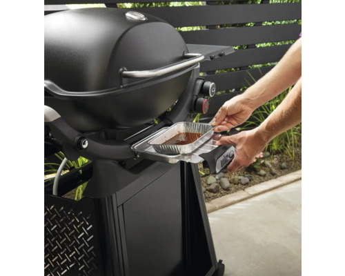Barbecue Weber avec une personne insérant un bac de récupération