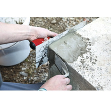 Une personne lisse du béton avec une taloche.