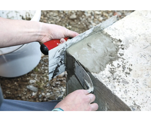 Une personne lisse du béton avec une taloche.