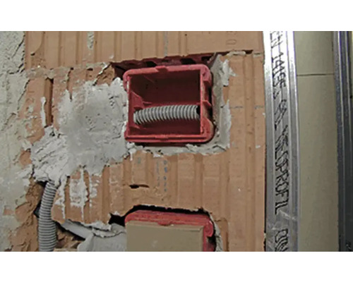 Installation d''une boîte d''appareil dans un mur en briques avec un tube vide.