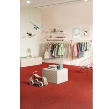 Magasin de vêtements pour enfants avec des robes, des avions jouets et des jouets en bois sur un tapis rouge.