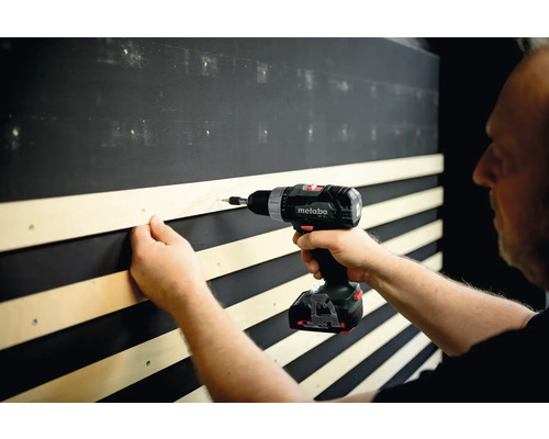 Handwerker befestigt Holzlatte mit Akku-Bohrschrauber an Wand