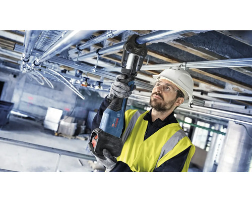 Handwerker montiert Rohrleitungen mit einer Presszange an der Decke.