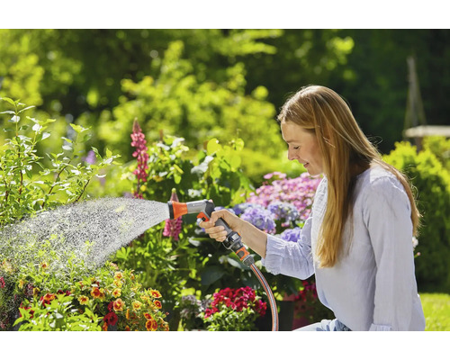 Femme arrosant des plantes avec un tuyau d''arrosage dans un jardin