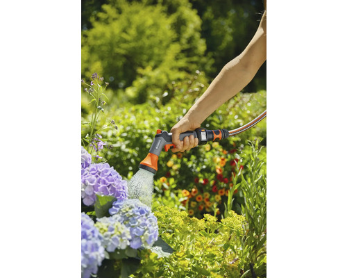Une personne arrose des fleurs avec un équipement de jardin Gardena.