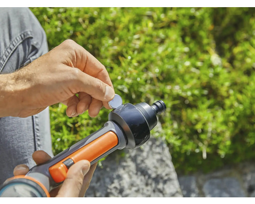 Une personne insère une pile bouton dans un pistolet d''arrosage