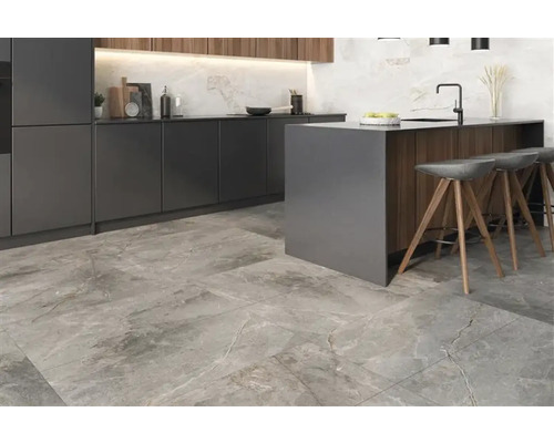Cuisine moderne avec îlot de cuisine, tabourets de bar et carrelage au sol imitation pierre.