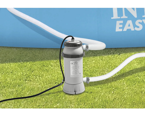 Pompe de filtration Intex avec tuyaux sur gazon devant une piscine