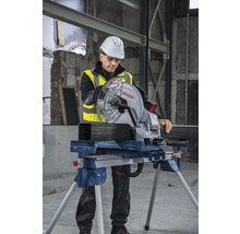 Un ouvrier en vêtements de travail utilise une scie circulaire à métaux Bosch pour couper un tube métallique.