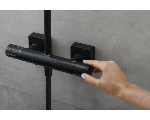 Schwarze Thermostatbatterie im Badezimmer wird von einer Hand bedient