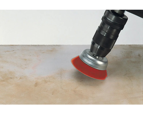 Une perceuse avec un accessoire de brosse nettoie une surface.