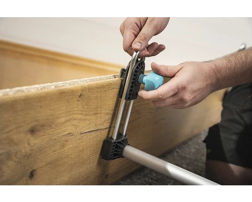 Un utilisateur fixe une planche de bois à l''aide d''un outil de montage.