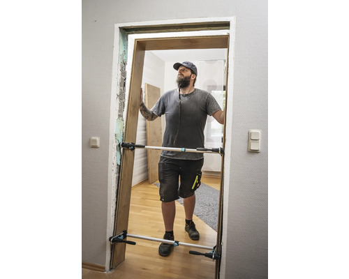 Un homme installe une porte avec un écarteur de porte.