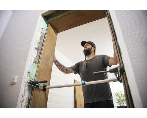 Artisan montant un cadre de porte en bois avec une règle