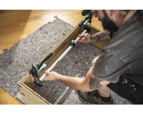 Un artisan fixe une barre d''écartement entre deux côtés d''un cadre en bois