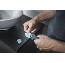 Mann benutzt ein Fugenwerkzeug im Badezimmer für Silikonfugen.