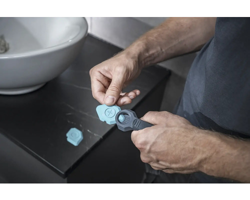 Mann benutzt ein Fugenwerkzeug im Badezimmer für Silikonfugen.