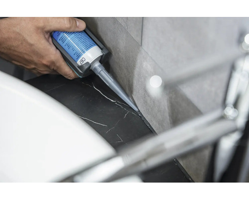 Eine Person trägt Silikon auf eine Marmoroberfläche auf.